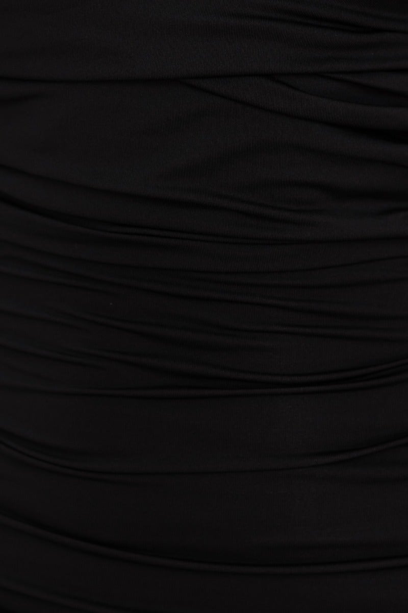 Close-up of black bodycon dress fabric with ruched detailing, showcasing soft material and elegant texture.