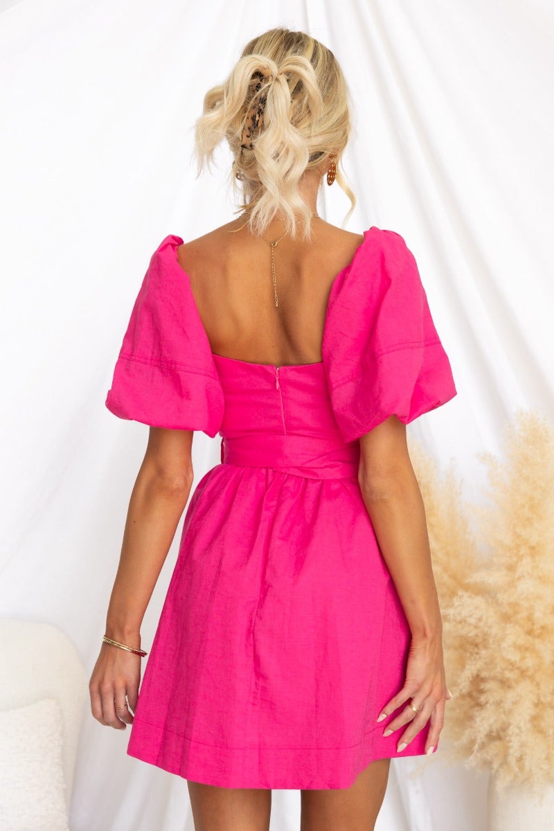 Back view of a pink flamingo dress with puff sleeves, elastic at cuffs, and invisible zip, showcased on a model.