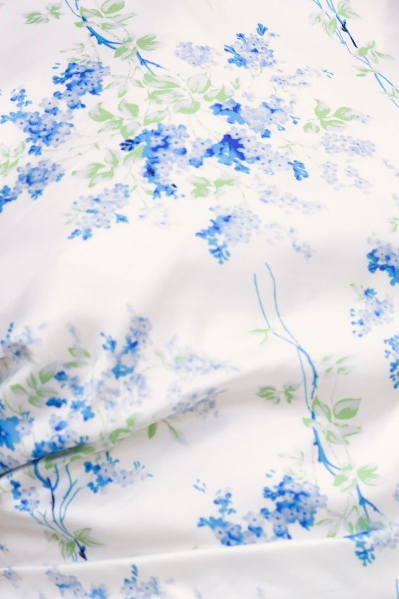 Floral print fabric close-up featuring blue and green flowers on a white background, ideal for a maxi dress.