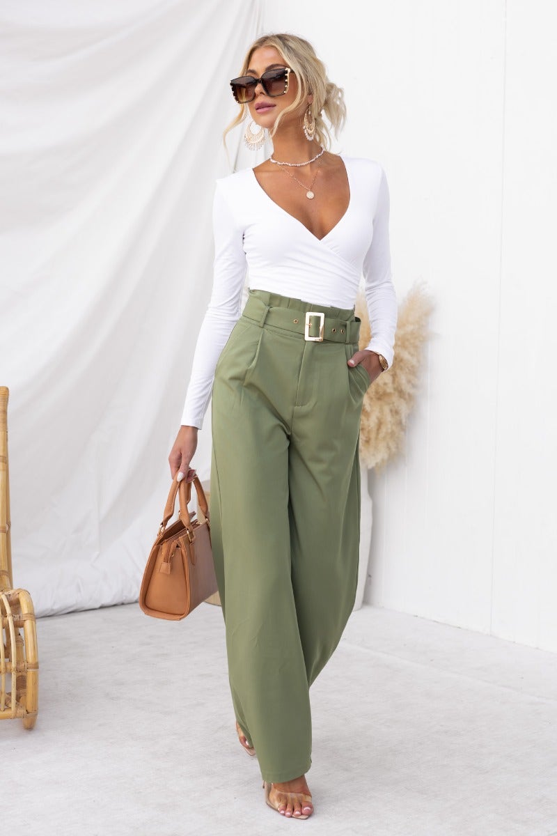 Model wearing No Strings Pants with paperbag waist and removable belt, styled with a white top and sunglasses.