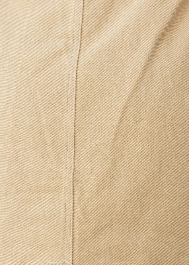 Close-up of light beige fabric texture with visible stitching, showcasing soft denim material for a stylish look.