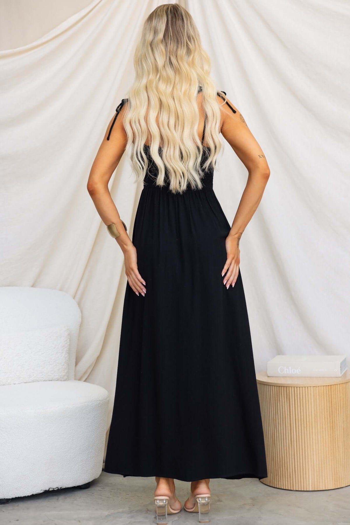 Back view of a woman in a black Damico Maxi Dress with tie straps and a flowy silhouette.