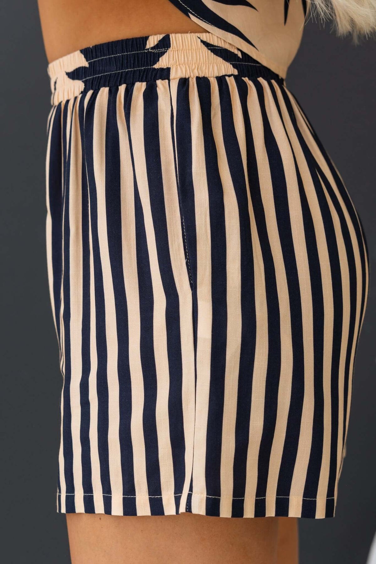 Side view of Hadley Shorts featuring navy and cream stripes, elastic waistband, and pockets, perfect for summer wear.