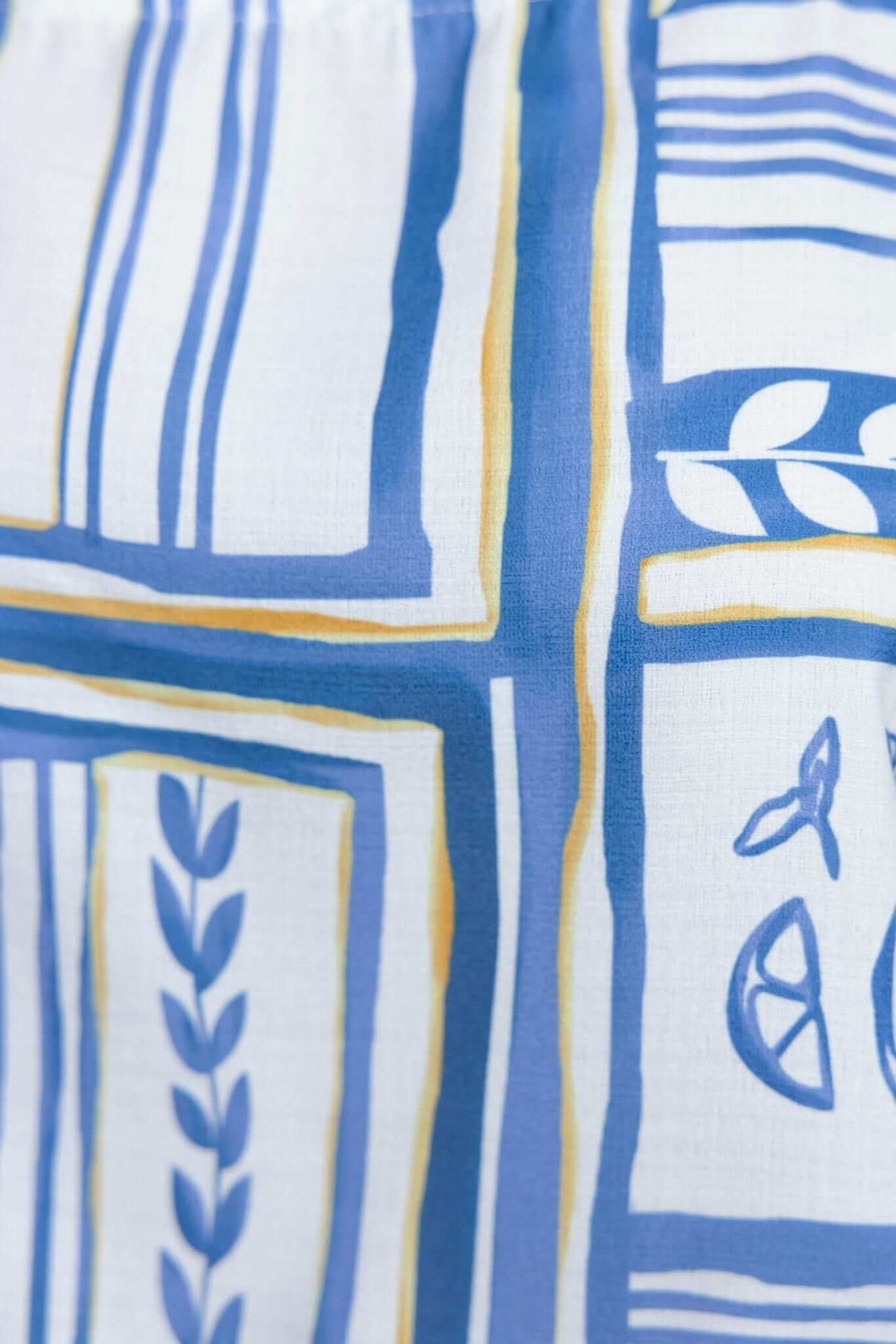 Stylish fabric detail of Minxie Top featuring geometric blue and yellow patterns on a white background.