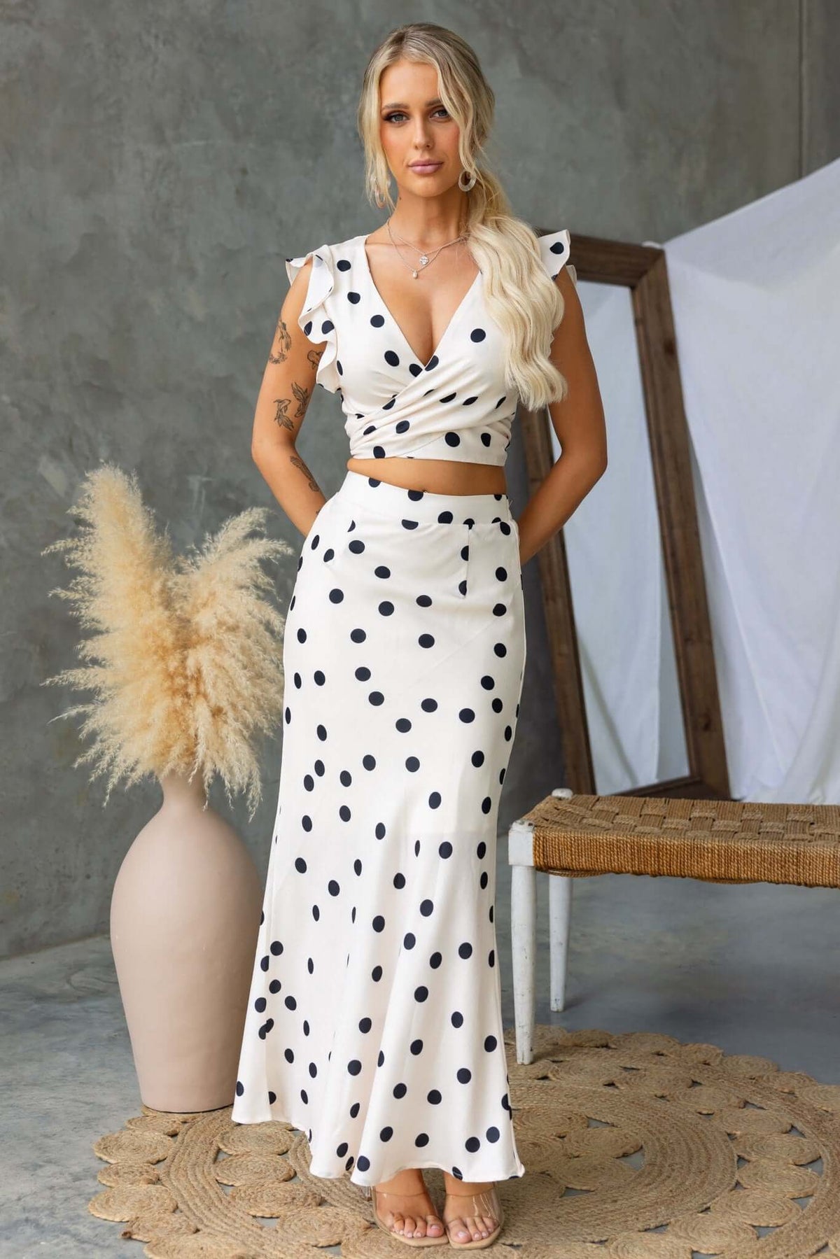 Louie Top in white with black polka dots, featuring a V-neckline and wrap-look, styled with matching skirt.