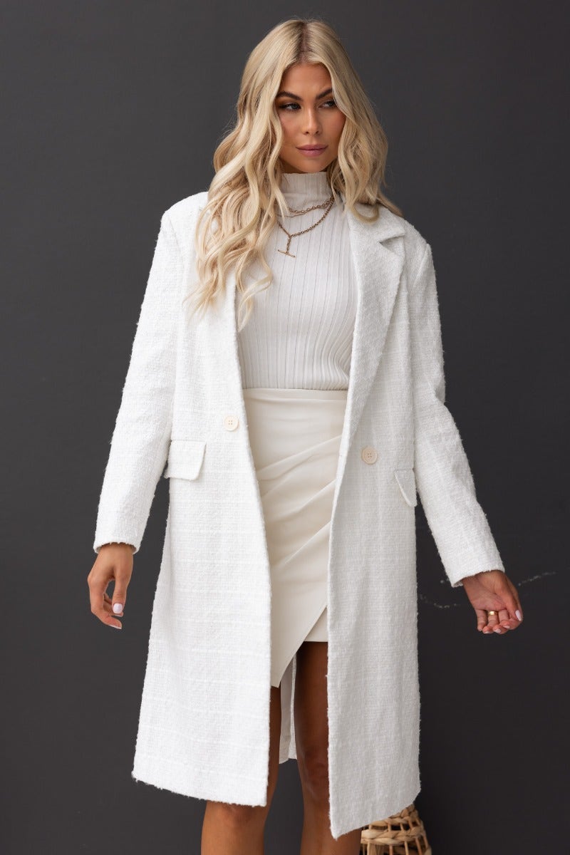 Zadie Coat in white tweed, longline fit with collar, button closure, and pockets, styled with a ribbed top and skirt.