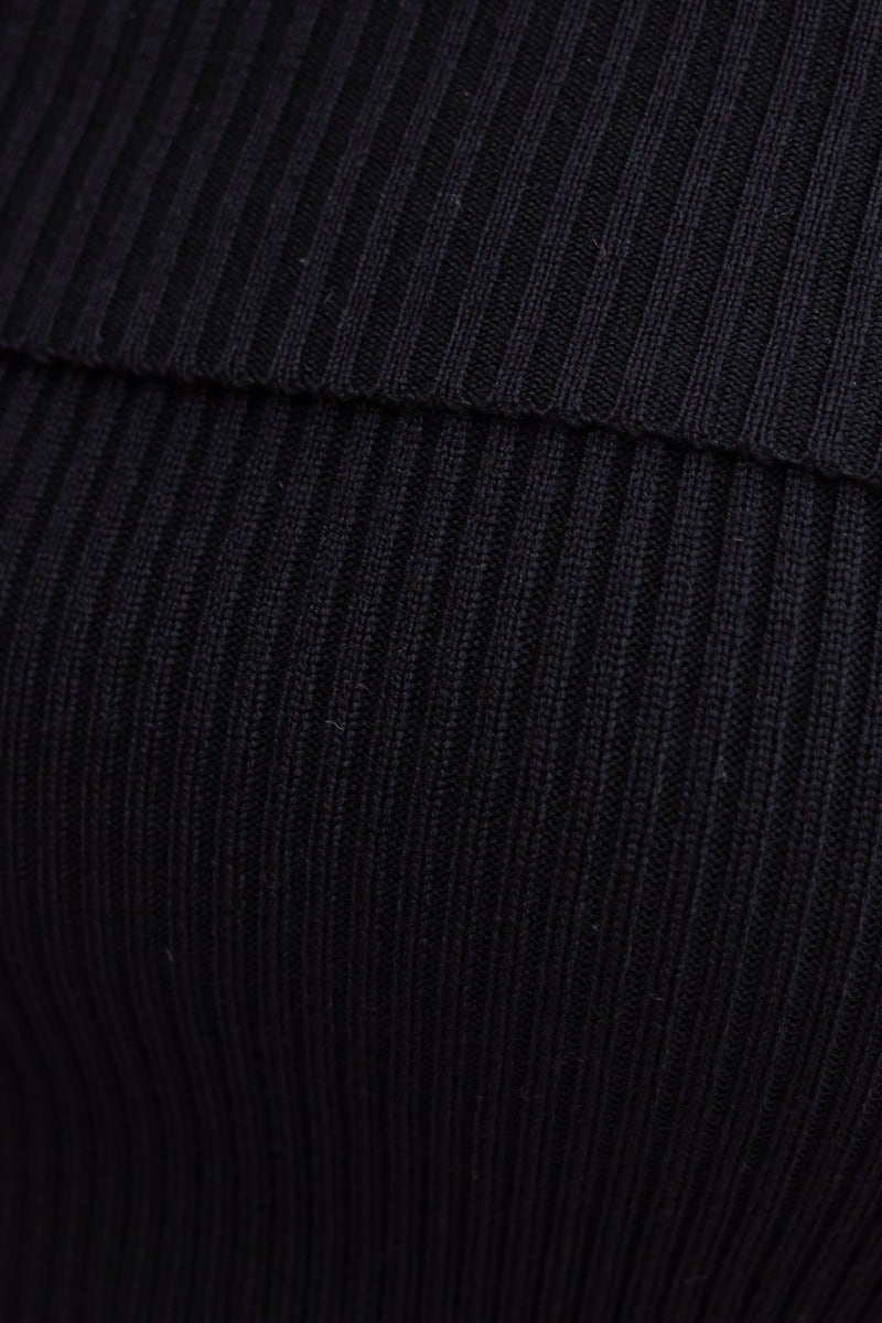 Close-up of black ribbed knit material top, featuring an off-shoulder neckline and textured fabric.