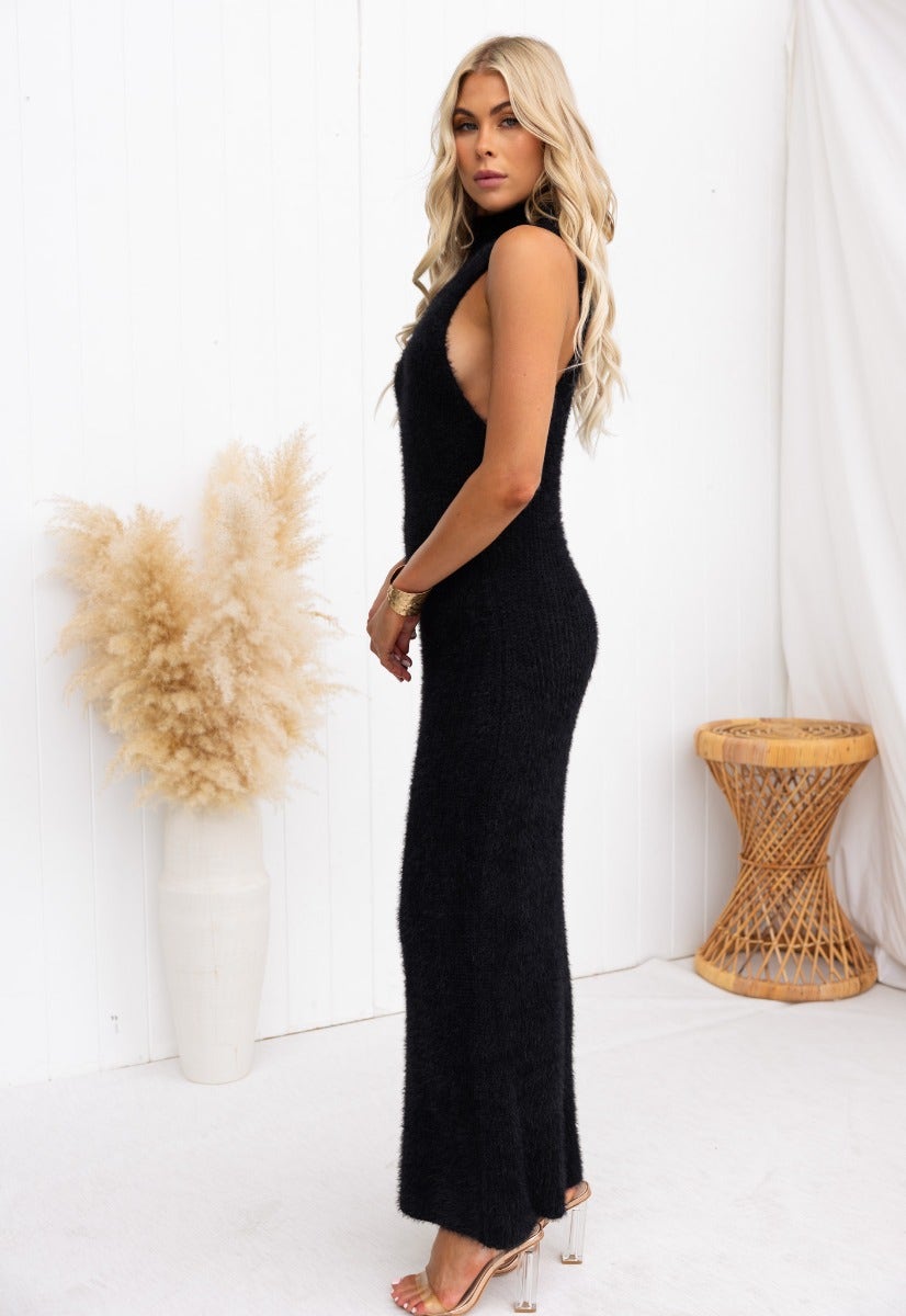 Model wearing the Watchful Eye maxi dress in black, showcasing its fluffy knit material and high neckline.