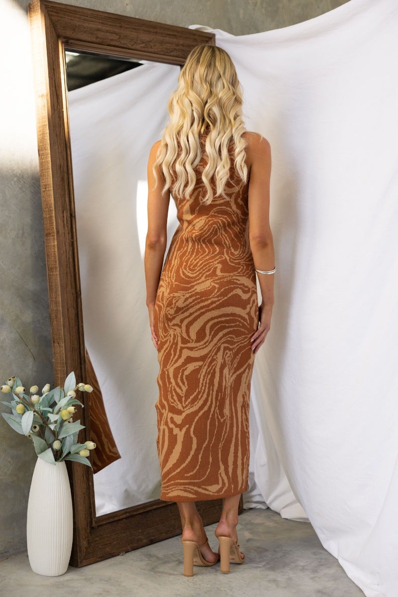 Back view of a model wearing a hypnotising brown knit maxi dress, showcasing side split and stylish design.