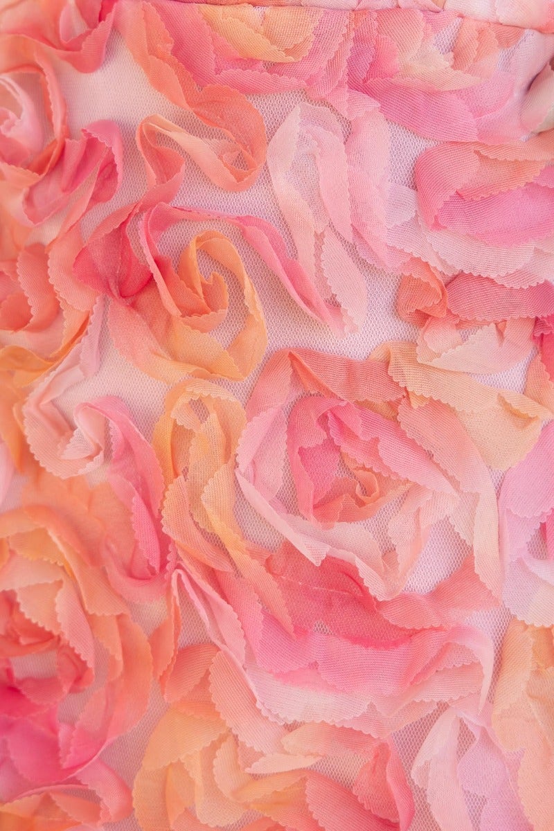 Close-up of a pink and peach floral fabric featuring layered, soft rose appliques.