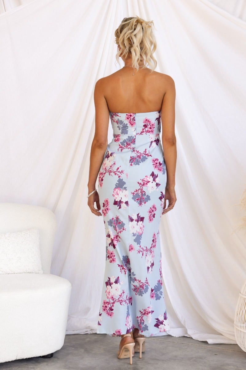Back view of the Tirana Maxi Dress featuring a floral print and strapless design, worn with elegant heels.
