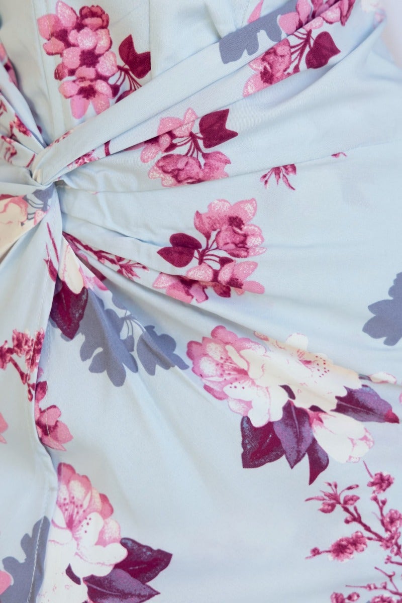 Floral print detail of the Tirana Maxi Dress, showcasing pink and purple flowers with a twist front design.
