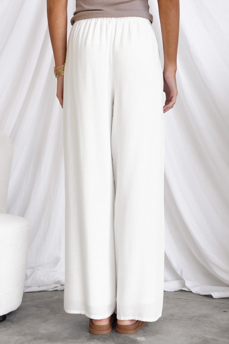 Back view of Corella Pants in white, featuring a relaxed fit and elastic waistband, styled with a neutral top.