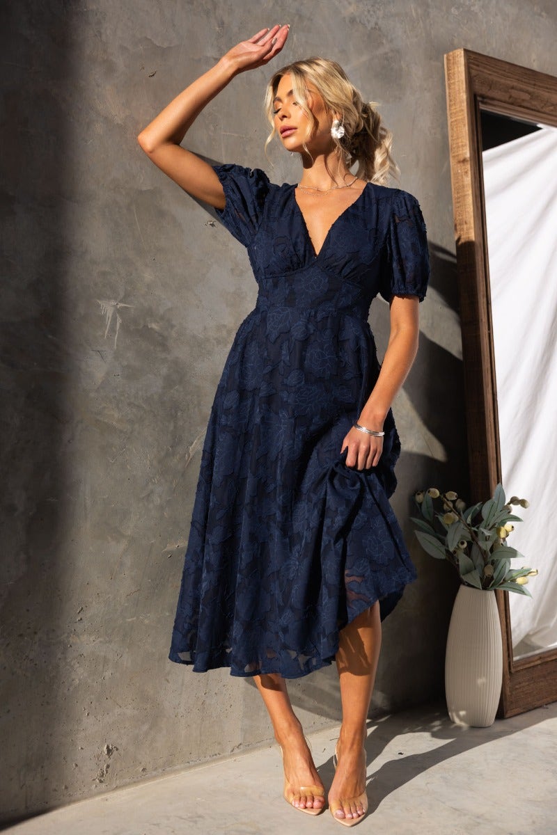 Narella Midi Dress in navy with embossed print, v-neckline, and elastic cuffs, model wearing size 6/XS.