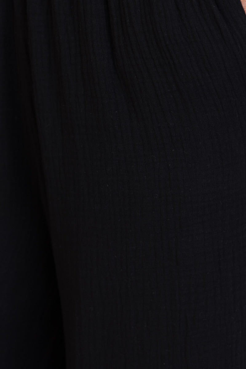 Close-up of black cotton blend Eureka pants featuring textured fabric and elastic waistband.