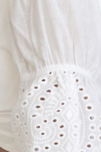 Close-up of Corbi Top featuring elastic sleeves and intricate Anglaise detailing in pure white cotton.