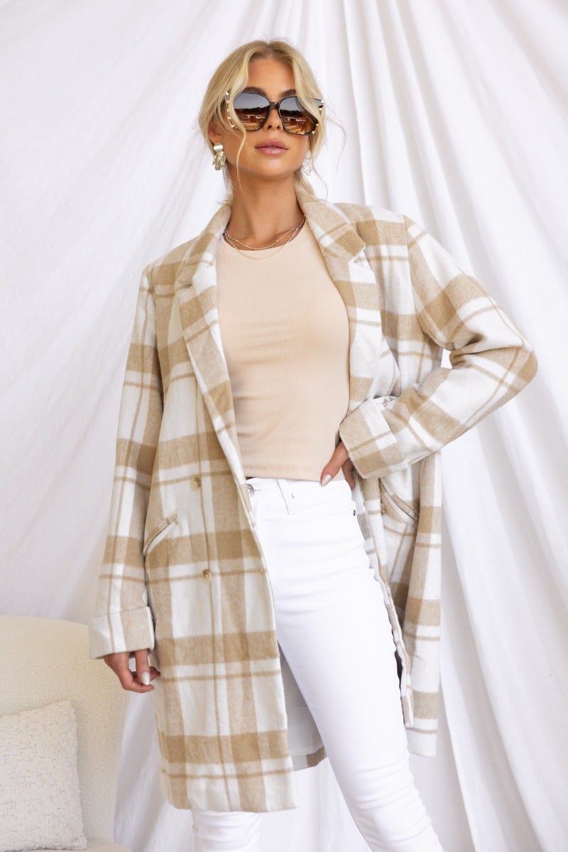 Model wearing the Sabine Coat, a plaid print coat, styled with a beige top and white jeans.