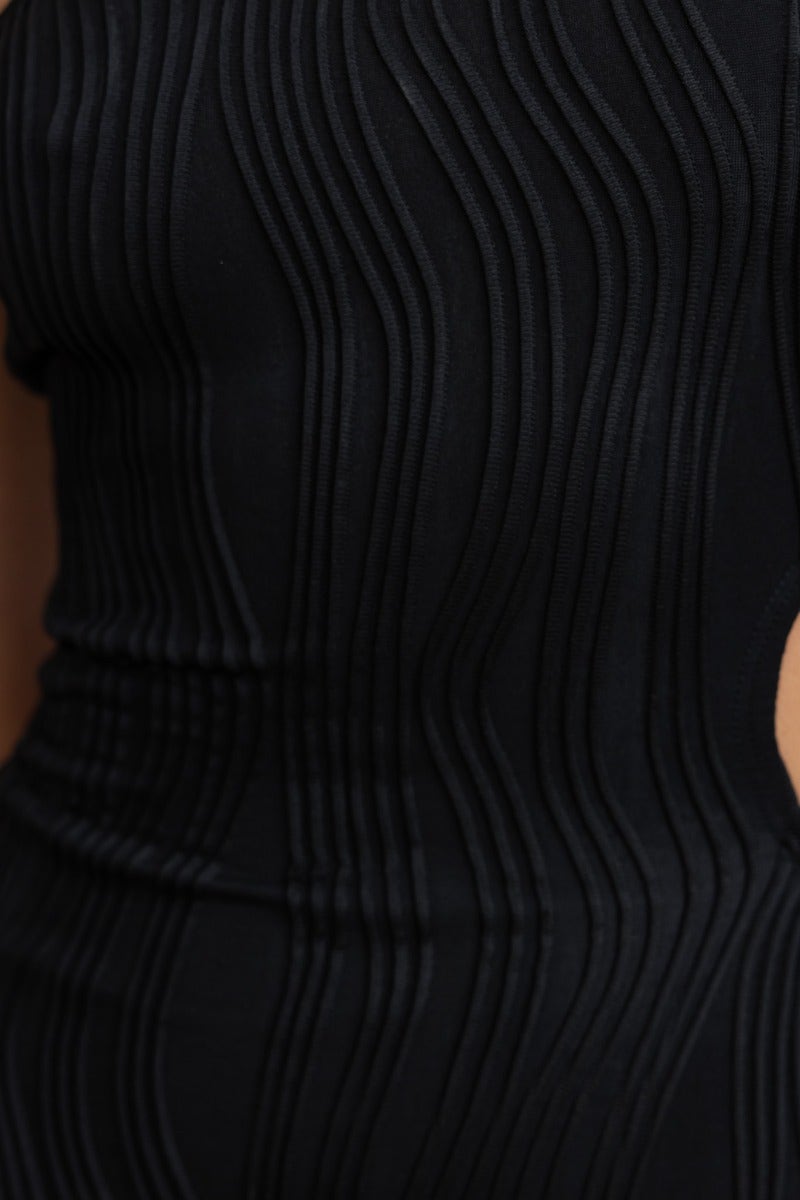 Close-up of black textured midi dress featuring stylish wave pattern and one-shoulder neckline.