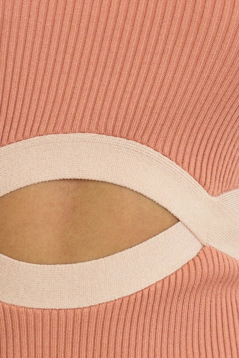 Close-up of ribbed knit fabric with a cut-out detail showcasing a waist design, in a soft pink hue.