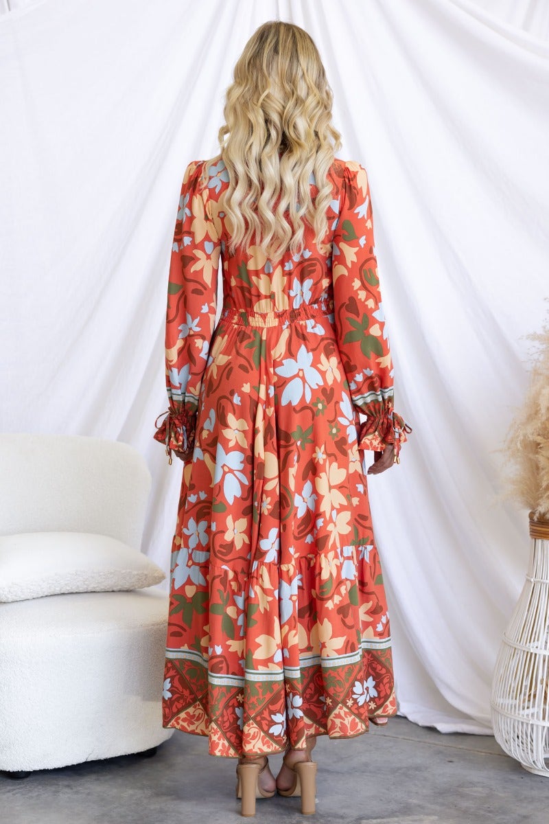 Model showcasing the back view of the Taniah Maxi Dress with floral print and V-neckline against a soft backdrop.