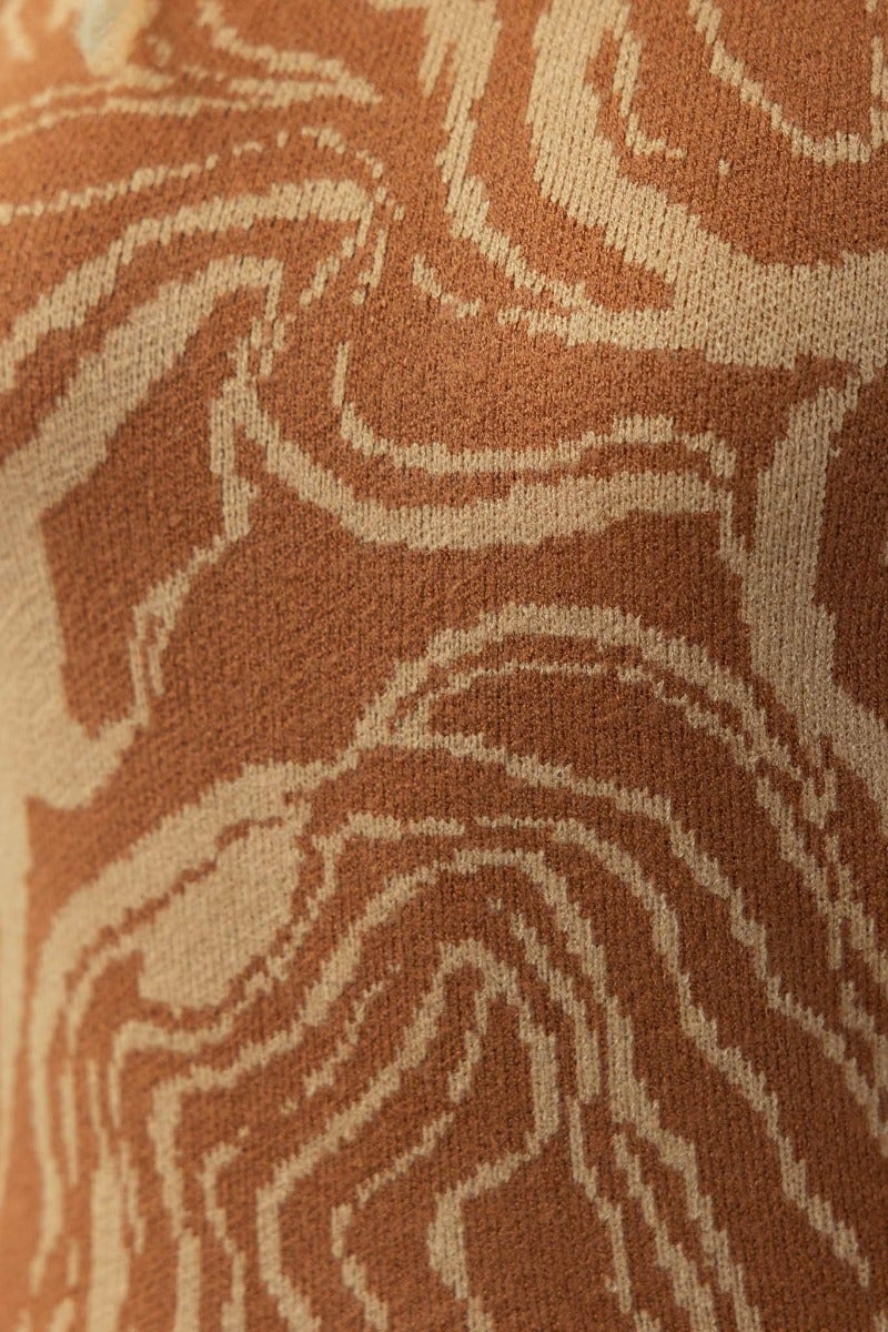 Close-up of hypnotizing maxi dress fabric in earthy tones with intricate pattern and soft texture.