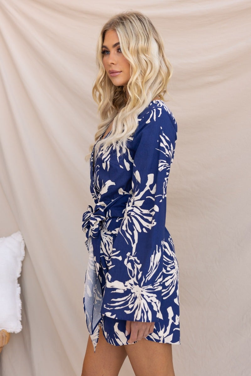 Model wearing the Take Chances Dress, a navy floral print dress with V-neckline and fabric tie.