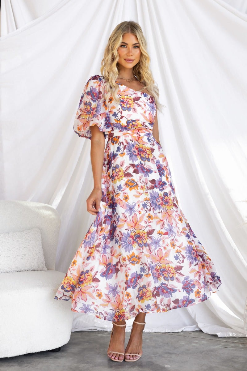 Floral print midi dress with one-shoulder neckline, model wearing it in a bright setting.
