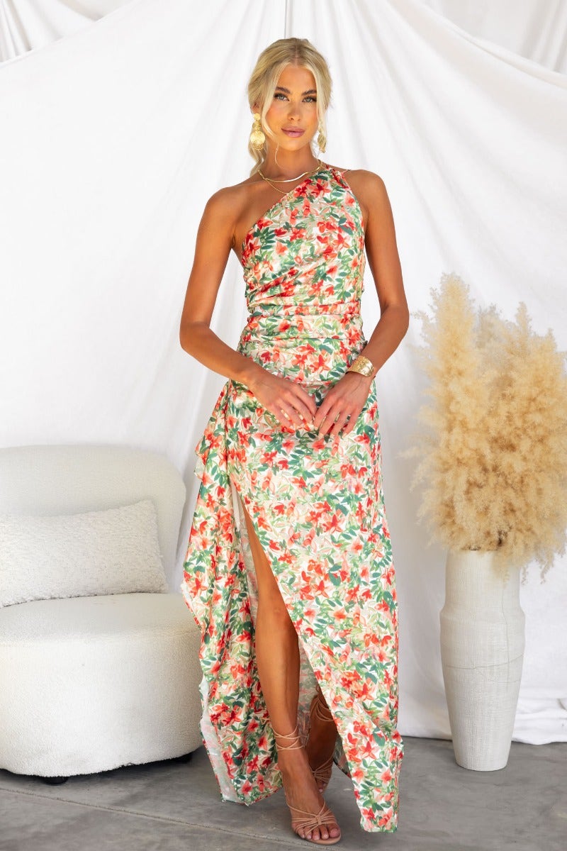 Model wearing a floral print Dimmi Maxi Dress with one-shoulder neckline and ruffle asymmetrical hem.