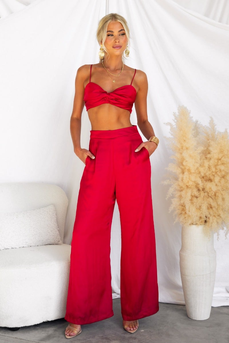 Model wearing Show Stopper Pants in red satin with a matching crop top, showcasing wide legs and side pockets.