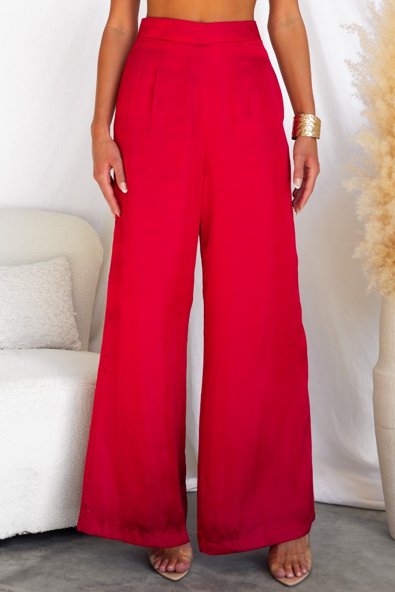 Show Stopper Pants in vibrant red satin, featuring wide legs, invisible back zip, and pockets for a chic look.