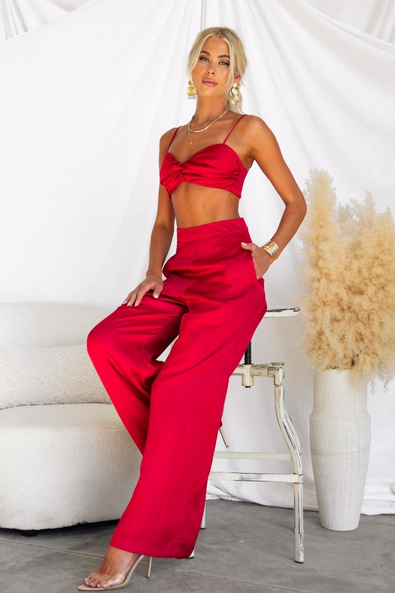 Model wearing Show Stopper Satin Pants in vibrant red with a matching crop top, showcasing wide legs and elegant styling.