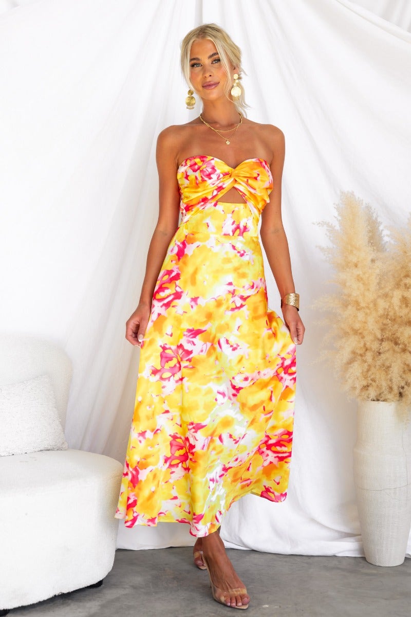 Model wearing Electric Touch Maxi Dress, a vibrant satin strapless dress with floral pattern and cut-out detail.