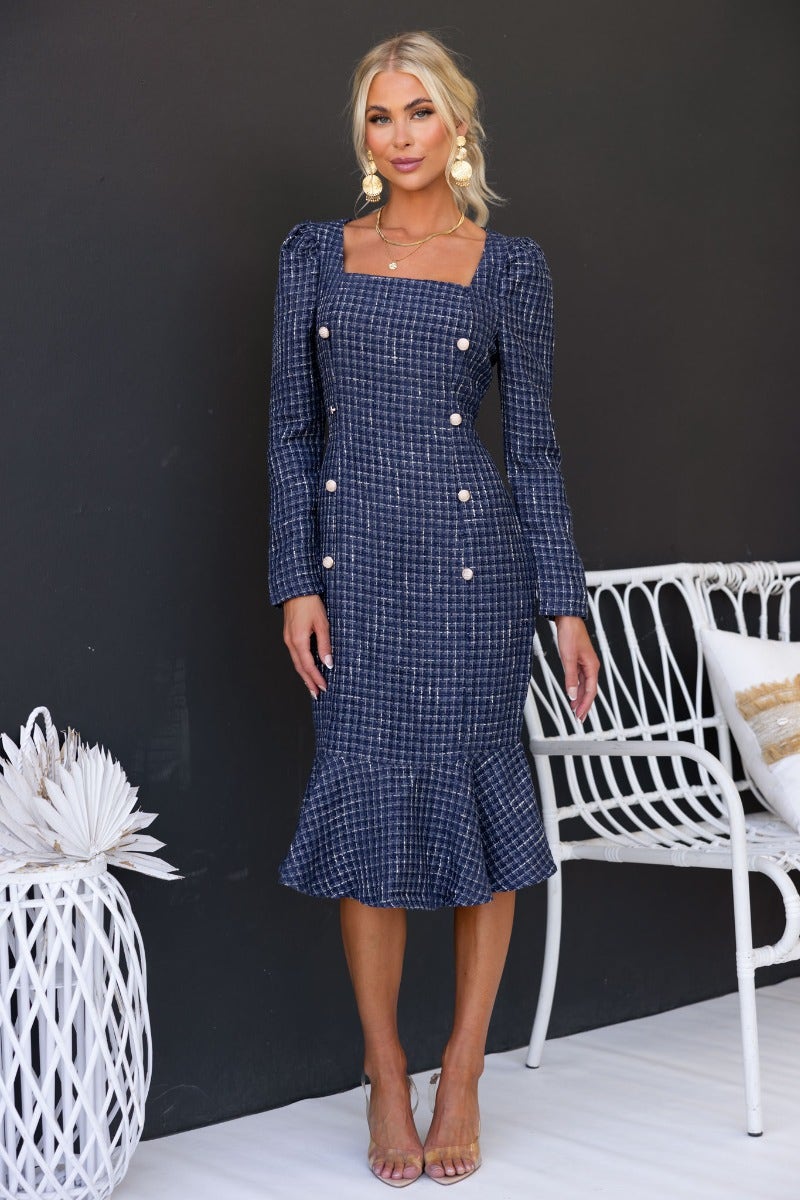 Model wearing a navy tweed midi dress with square neckline and gold button details, featuring a flared hem.