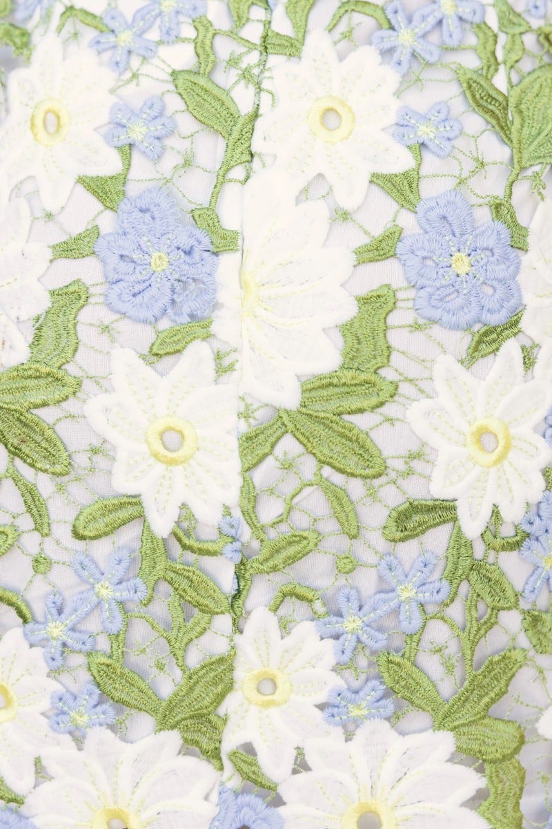 Delicate lace detail featuring flowers in white and blue, showcasing intricate embroidery on the See The World Dress.
