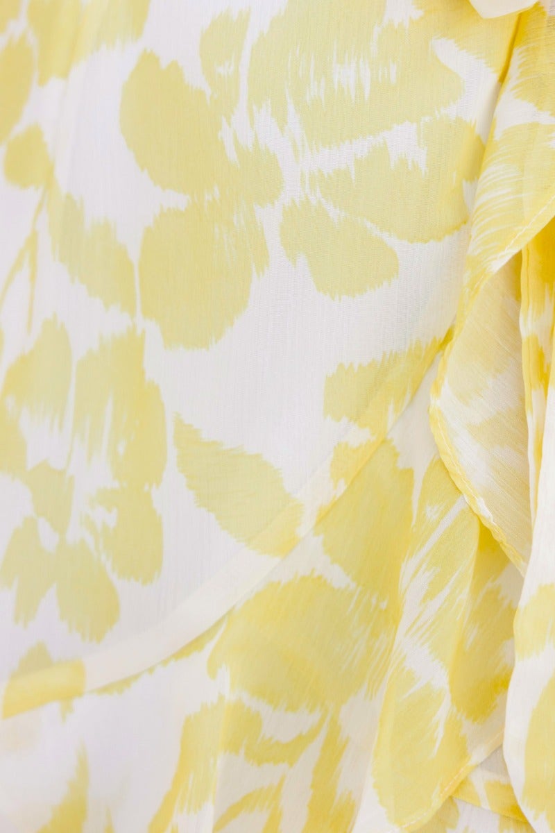 Close-up of yellow floral print fabric on a lightweight dress featuring frill details and delicate texture.