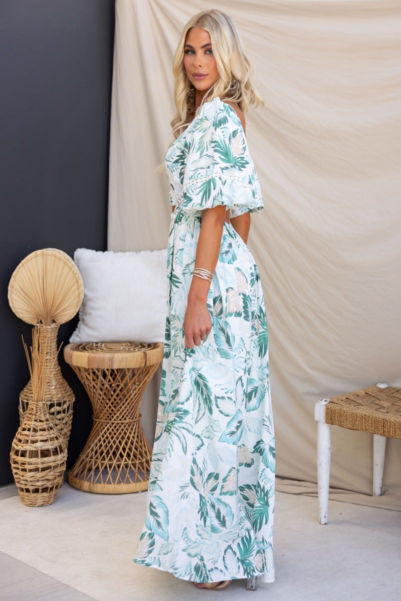 Model in Out Of Sight Maxi Dress featuring green floral print, V-neckline, and cut-out at waist.