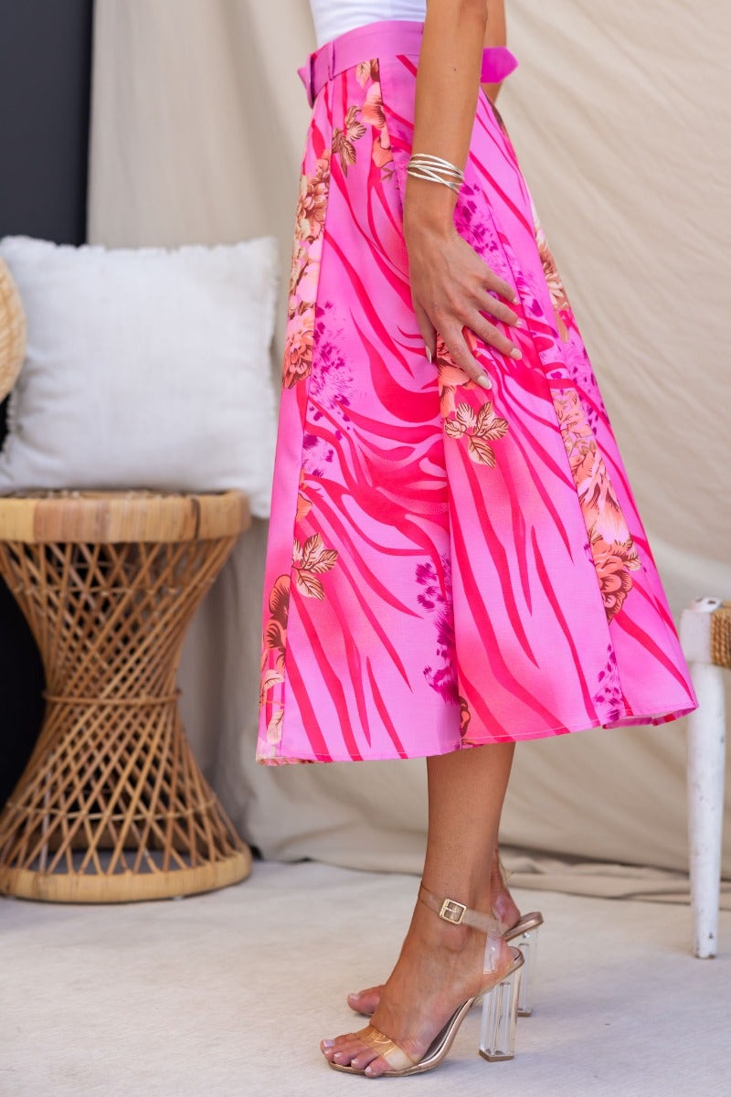Pink floral midi skirt with a high waist, removable belt, and flowy design, showcased in a chic setting.