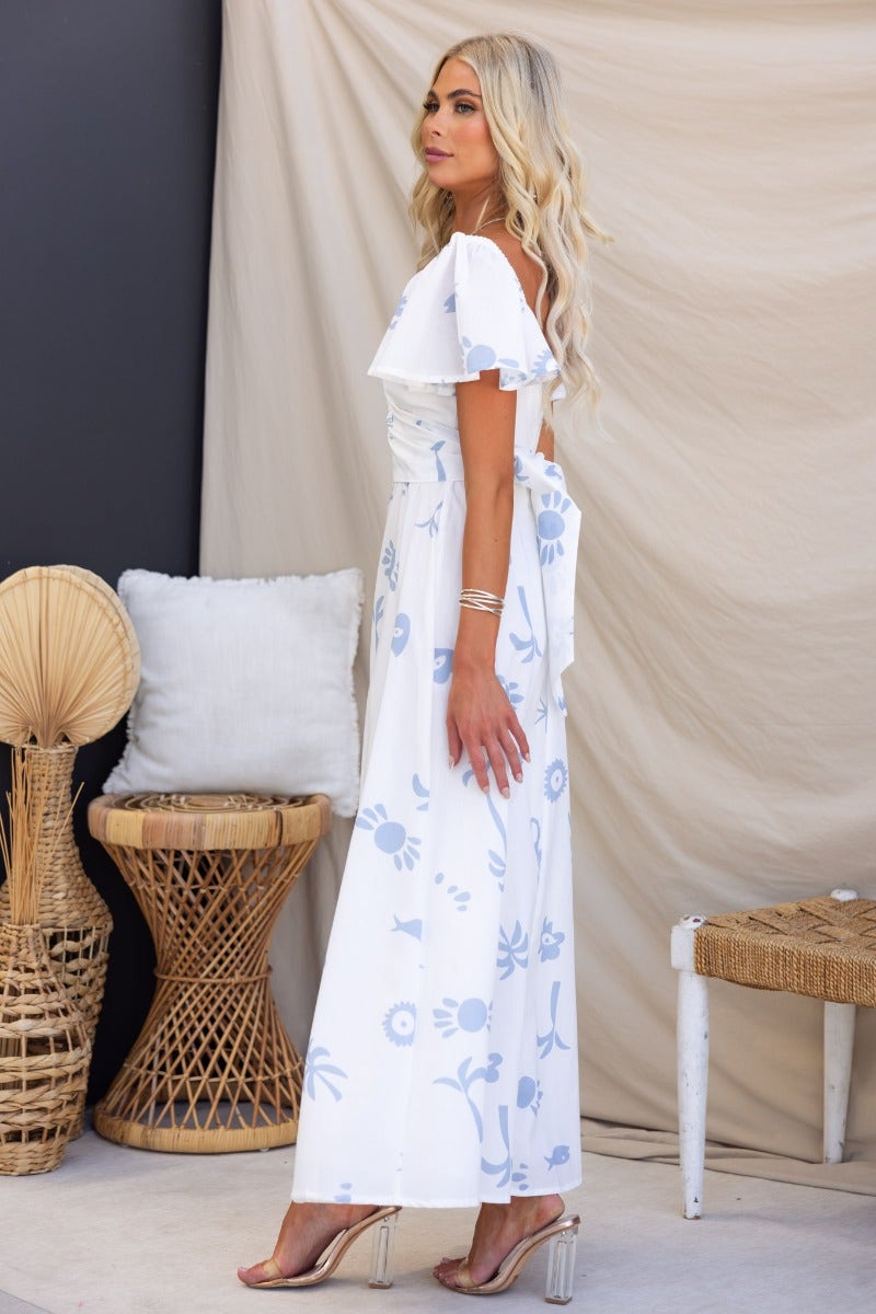 Model wearing Fermina Wrap Maxi Dress with floral design, showcasing its elegant wrap tie and off-shoulder sleeves.