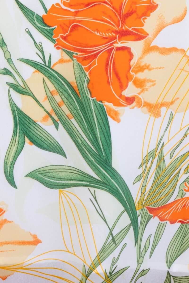 Close-up of vibrant floral print featuring orange flowers and green leaves, perfect for a tranquil maxi dress.