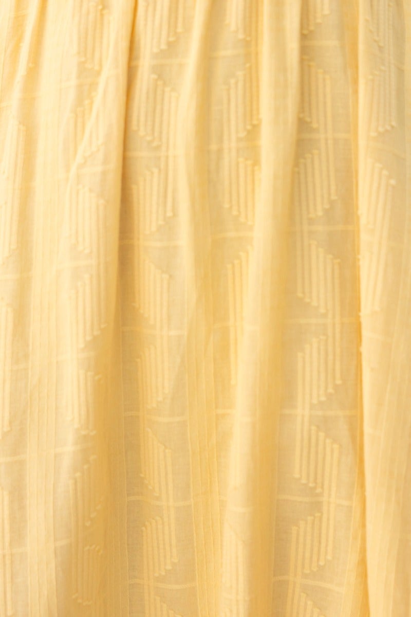 Close-up of textured yellow fabric featuring a geometric pattern, ideal for the Fiji Maxi Dress design.