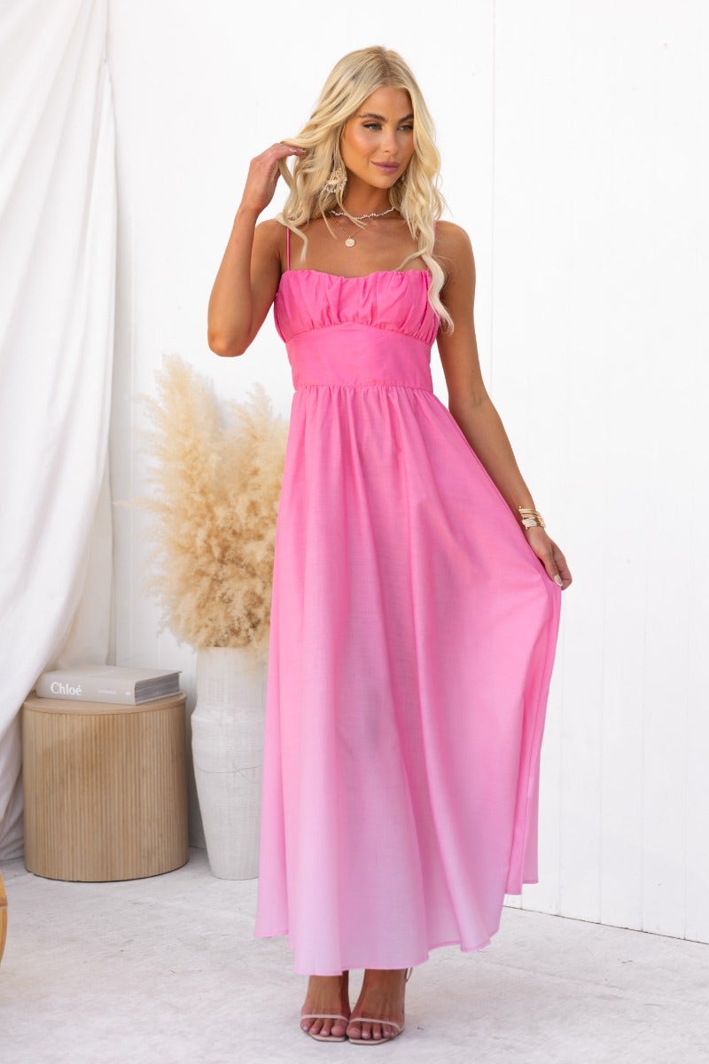 Model wearing a pink Blank Space Maxi Dress with adjustable straps, showcasing a flowy design against a neutral backdrop.