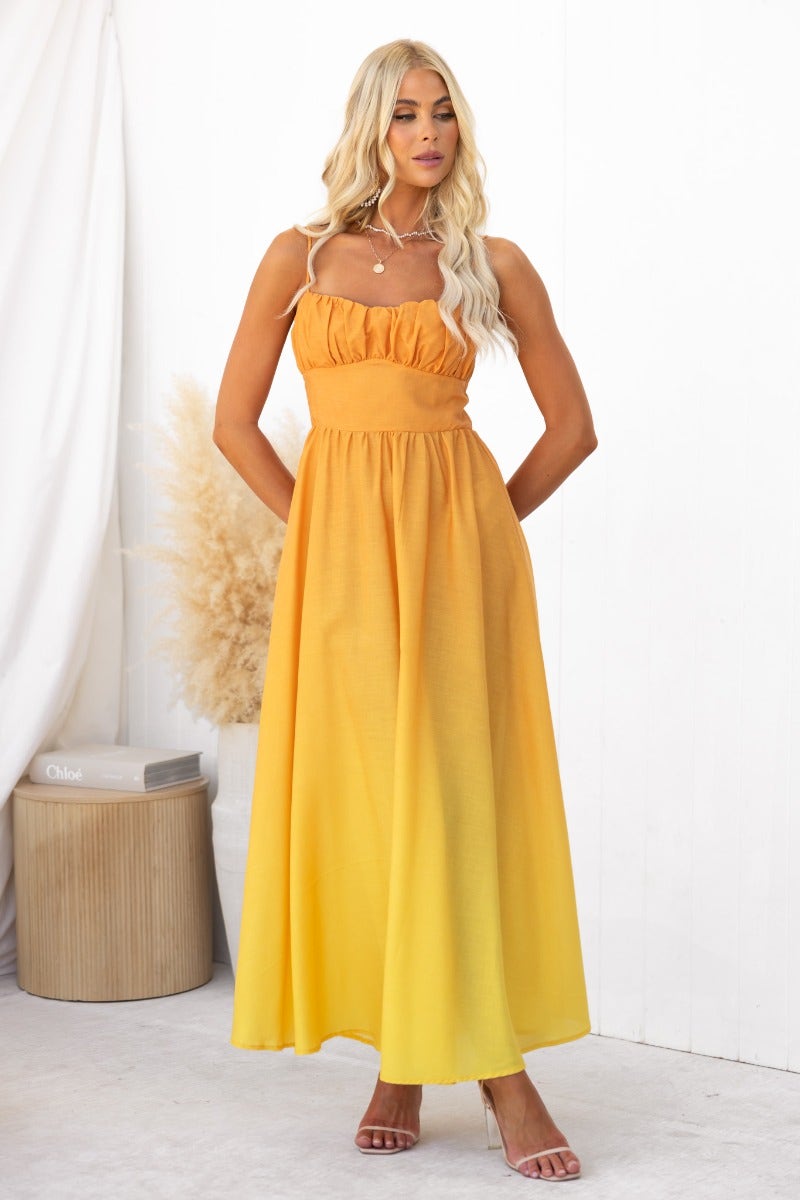 Model wearing a bright yellow cotton blend maxi dress with adjustable straps and a flowing skirt.