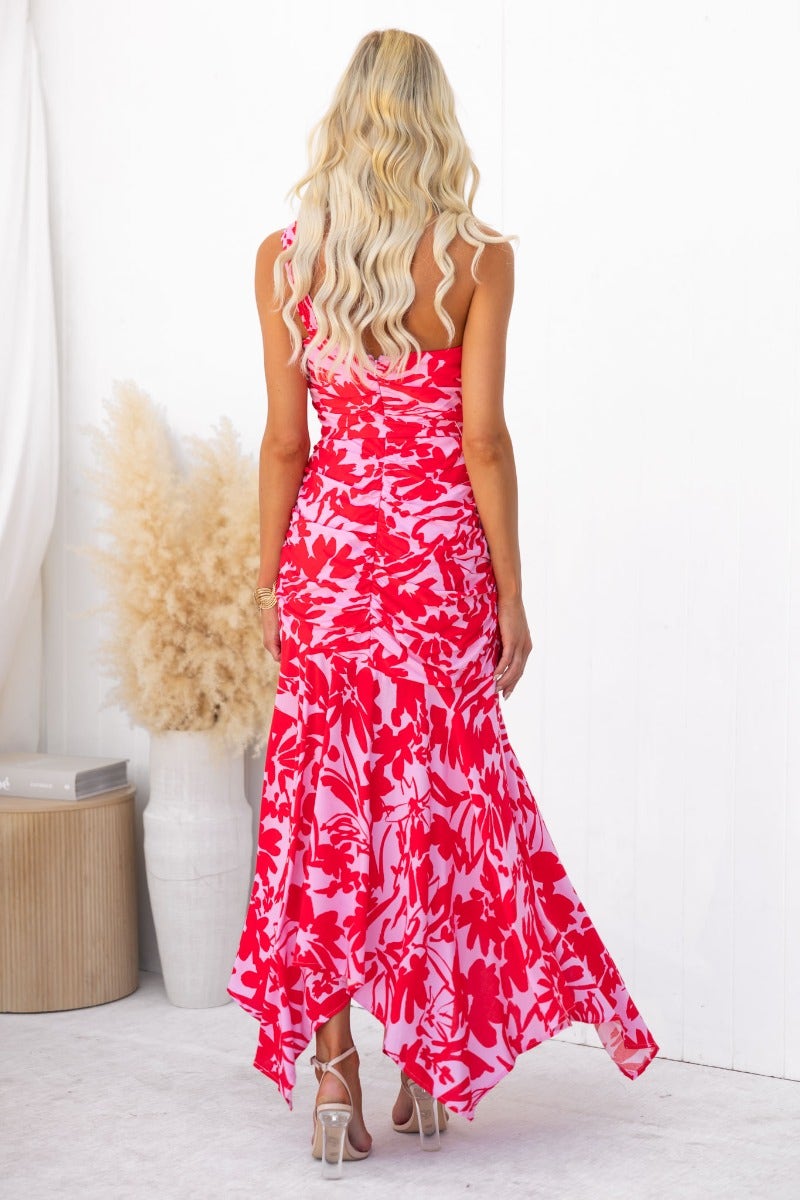 Back view of the Escoda maxi dress featuring a vibrant floral print, one-shoulder design, and asymmetric hem.