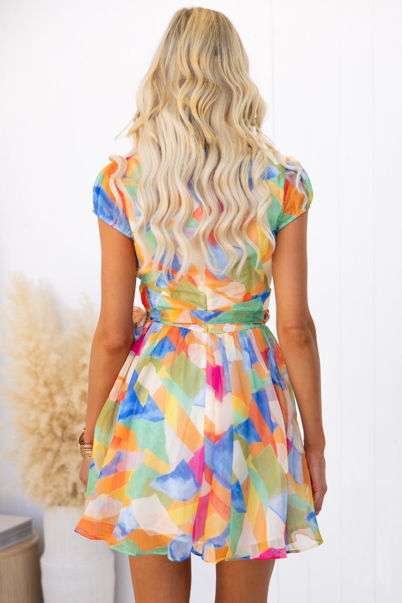 Colorful wrap dress with V-neck and tie at the waist, shown from the back, perfect for a stylish summer look.