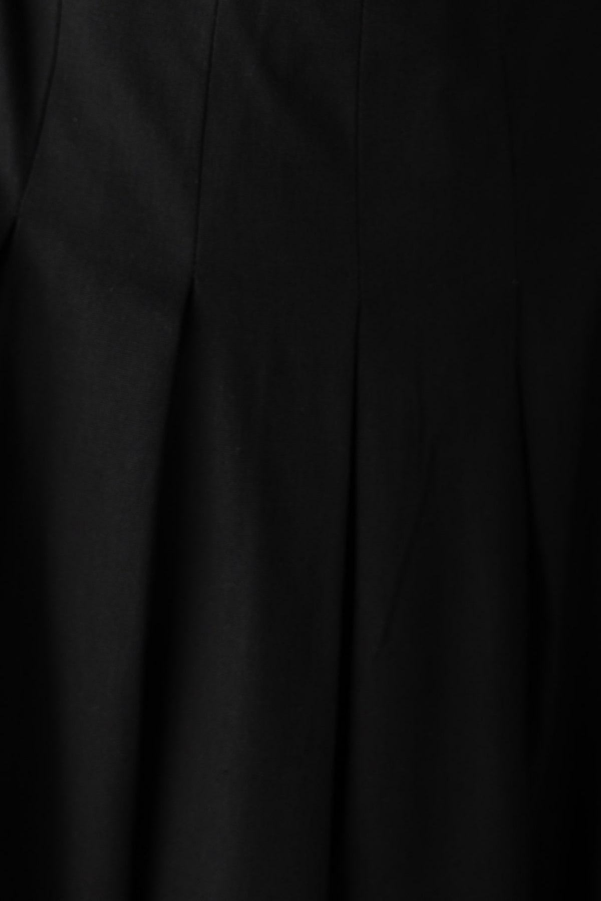 Close-up of a black linen maxi dress featuring pleats and a textured fabric for a stylish look.