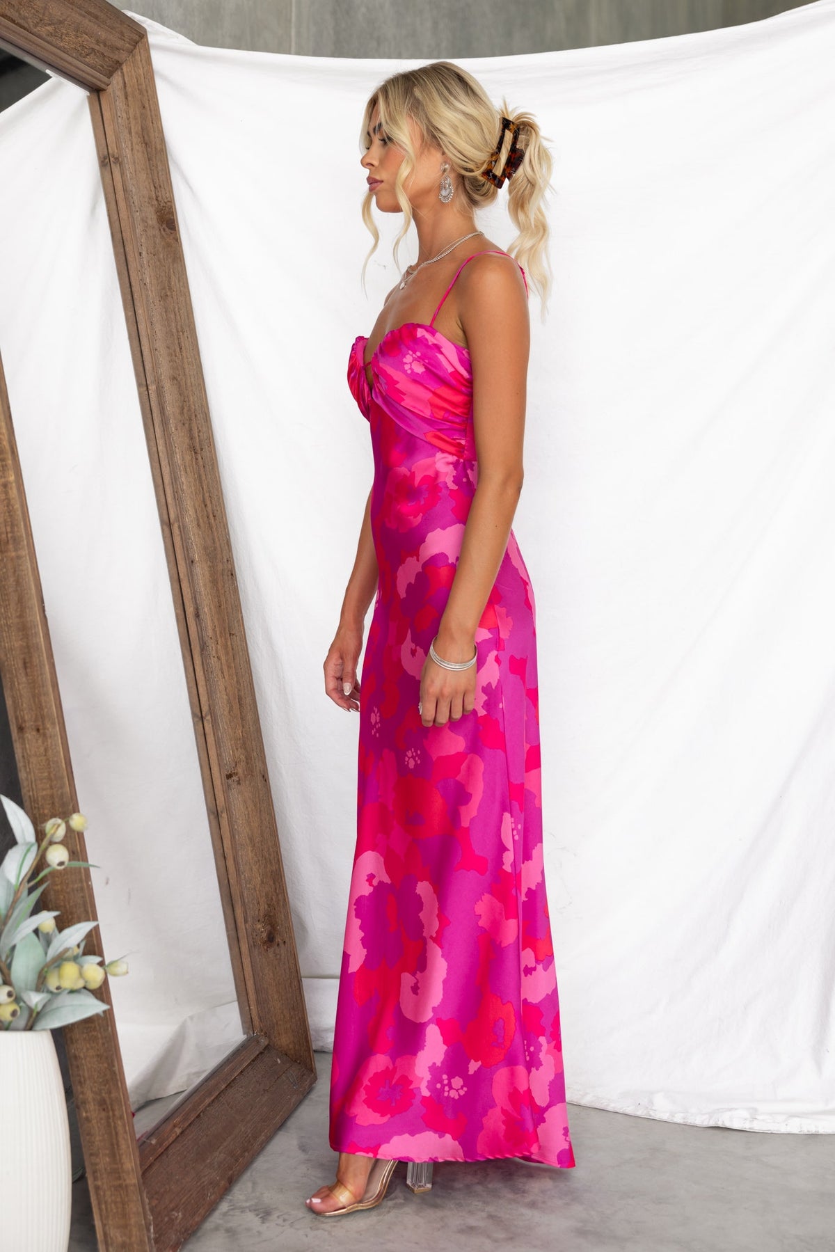 Floral print pink satin maxi dress with adjustable straps and keyhole detail, styled by a model in a modern setting.