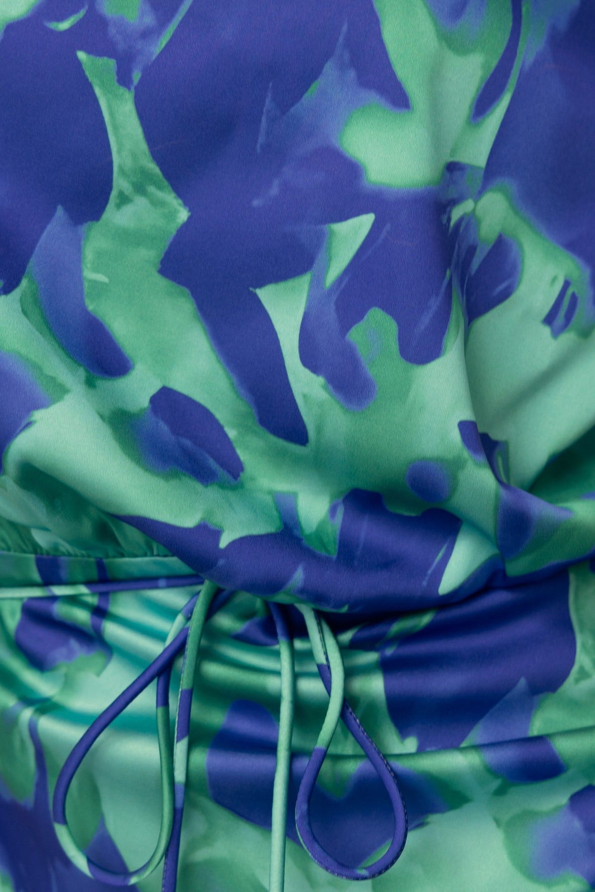 Close-up of floral print fabric in green and blue, highlighting the decorative tie detail of the maxi dress.