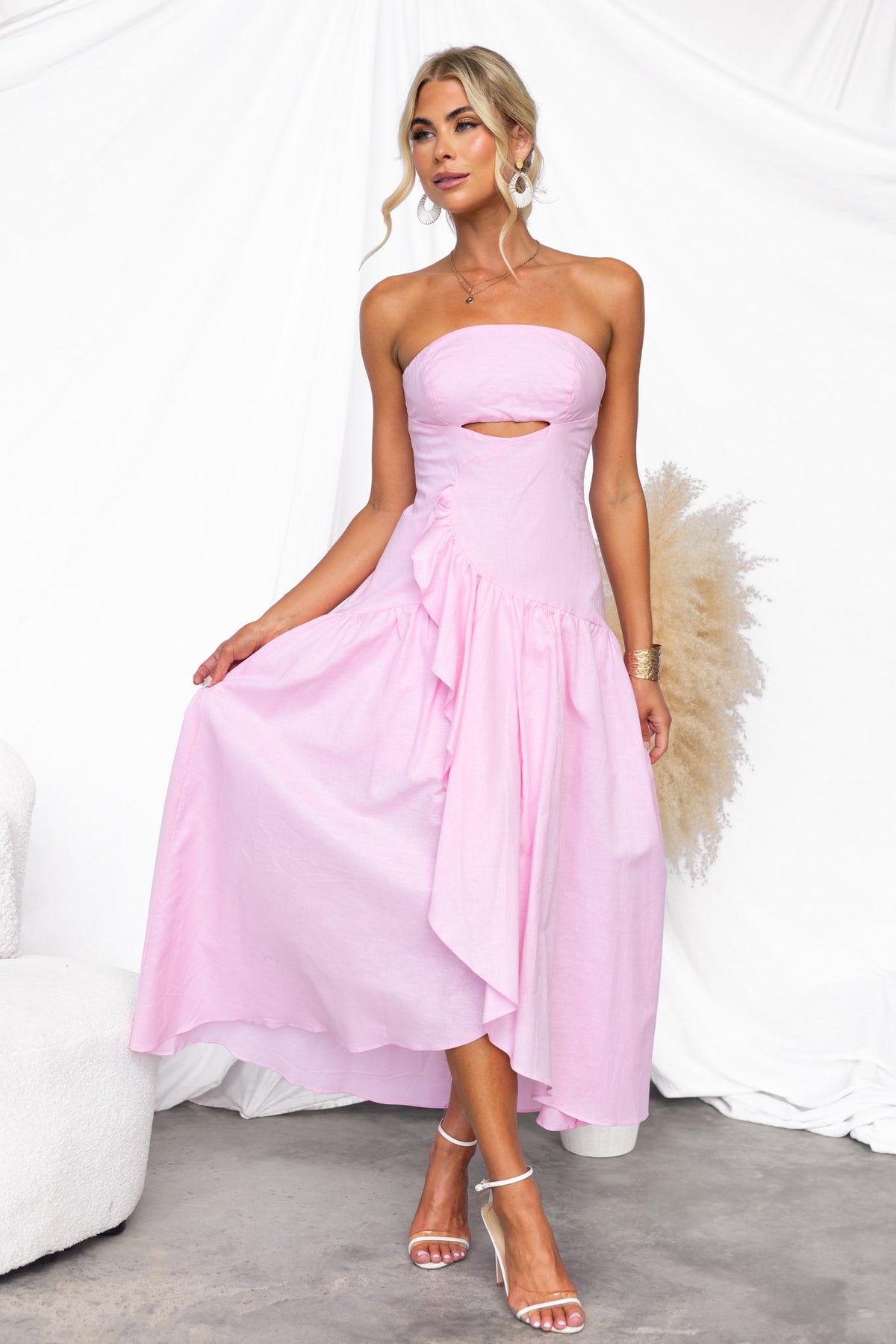 Model wearing a pink Dancing Queen Maxi Dress with strapless design and asymmetric hem.