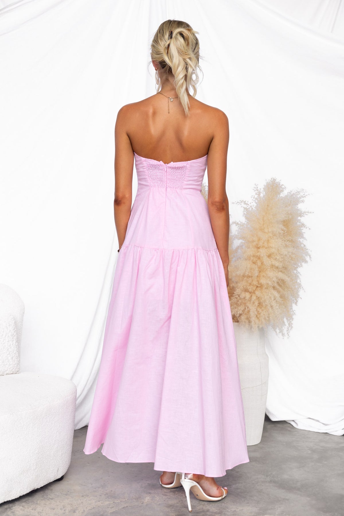 Back view of a strapless pink Dancing Queen Maxi Dress with elastic back and asymmetric hem.