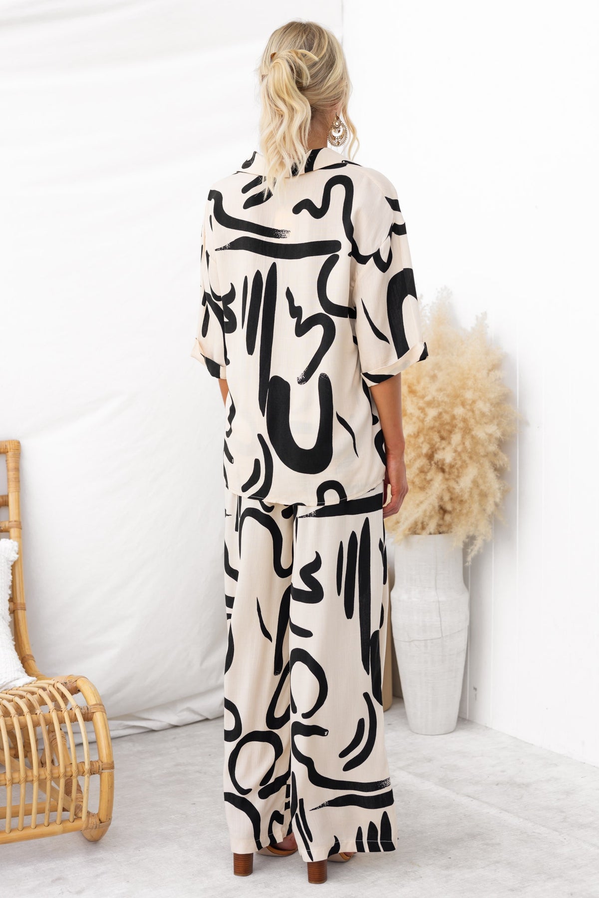 Model wearing Arwen Set, featuring abstract print shirt and pants, showcasing a stylish, relaxed back view.
